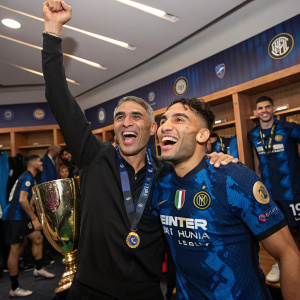 Achraf Hakimi and Lautaro Martinez celebrating in locker room after winning UEFA Champions League. Teammates and coaches in background