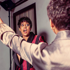 Tia Mowry, Hollywood star, in a candid photo shoot. Close-up on her face, showcasing her short hairstyle. She wears a stylish black and red blazer.