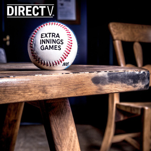 Ad for DirecTV's MLB Extra Innings package featuring a baseball with the text 'Great Extra-Inning Games' and MLB branding. Shot on a rustic wooden table.