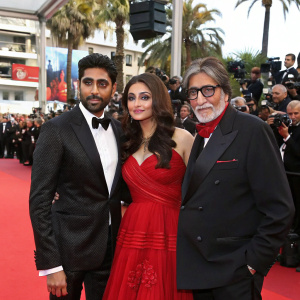 Aishwarya Rai, Abhishek Bachchan, and Amitabh Bachchan attending a bustling Cannes Film Festival. They pose for the paparazzi amidst a sea of fans and celebrities.