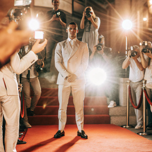 Cristiano Ronaldo, in formal suit, presenting at awards show. Red carpet, flashing lights, paparazzi in frenzy.