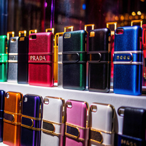 High-resolution photo of Prada phone cases in vibrant colors like red, green, orange, black, pink, and white, neatly arranged on a pristine white surface. Each case is meticulously designed to fit the smartphone perfectly, featuring the iconic Prada logo.