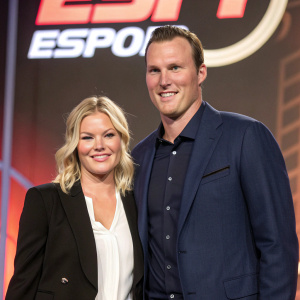 Elisha Cuthbert and Dion Phaneuf, smiling and posing at a sports awards ceremony. The backdrop features a large, bright 'ESPN' logo. Elisha, in a black blazer over a white blouse, with her blonde hair loose. Dion, with a short, styled haircut, is in a navy blazer.
