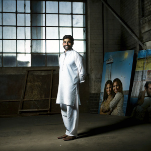 Abhishek Bachchan, dressed in a traditional kurta, standing in front of 'Paa' promotional backdrop. Indoor event setting, with film promotional images in background.