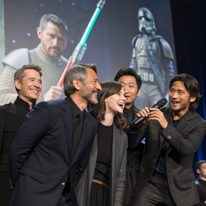 Ben Mendelsohn, Riz Ahmed, Mads Mikkelsen, Felicity Jones, Diego Luna, and Donnie Yen at the Star Wars Celebration. Wearing formal attire, posing with props and backdrop featuring Star Wars characters.