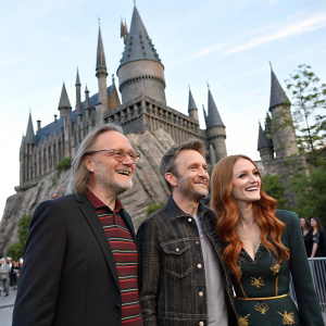 Gregory Nicotero, Chris Hardwick, and Lydia Hearst at the grand opening of Universal Studios' Wizarding World of Harry Potter. They stand before a majestic castle-like backdrop.
