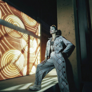 Jolyne Cujoh, from JoJo's Bizarre Adventure, standing in a dynamic pose. Backdrop features vibrant, swirling patterns of her Stand ability, Star Platinum