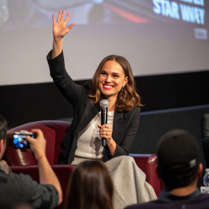 Natalie Portman at a Q&A session, waving and smiling, candid shot from a fan's camera.