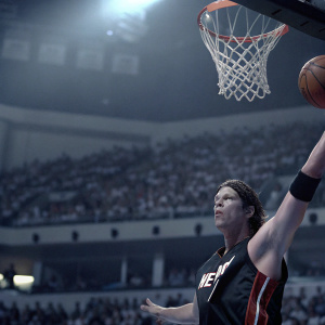 Mike Miller, dressed in black and red Miami Heat jersey, intense game moment. Crowded arena background.
