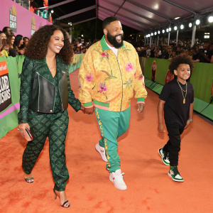 Nicole Tuck, Asahd Tuck Khaled, DJ Khaled, and Brian Robbins walking on a vibrant green carpet during the Nickelodeon Kids' Choice Awards event.