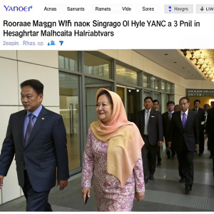 Screenshot from Yahoo News Singapore video. Rosmah Mansor, wife of former Prime Minister Najib Razak, arriving at Macc headquarters in Kuala Lumpur. Diverse group in business attire walking through a modern building entrance.