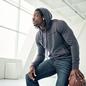 Robert Griffin III, wearing a fitted grey hoodie and jeans. Solo portrait. Sporty, modern studio setting.