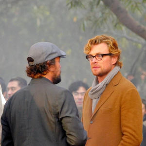 Leonardo DiCaprio, beard, casual cap, Simon Baker, curly hair, glasses. Crowd blurred. Film festival press event.