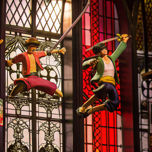 Figurines of Luffy and Zoro from One Piece. Action poses, set against a background of intricate gothic stained glass patterns.