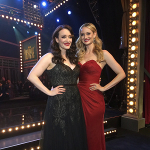 Kat Dennings and Beth Behrs at a Broadway show opening night, dressed in elegant evening gowns, standing on a lit stage