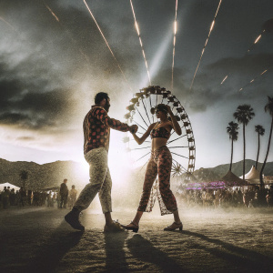 Drake and Bella Hadid dancing at Coachella. Desert festival, vibrant lights and crowds.