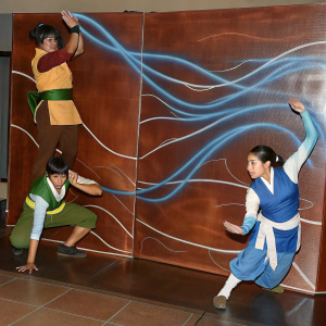 Illustration showcasing characters from Avatar: The Last Airbender in intense action scenes. Vibrant earth tones and swirling blue energy lines dominate the backdrop. Anime-style art