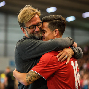 Jurgen Klopp, with glasses and light stubble, hugging Philippe Coutinho. Coutinho has a tattoo on his arm. Blurred audience in the background. Indoor sports hall