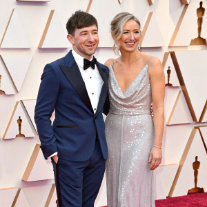 Barry Keoghan and Alyson Kierans on the Oscars red carpet. Both dressed in formal attire, Barry in a navy blue tuxedo and Alyson in a shimmering silver gown. They pose with smiles.