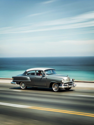 Vintage car going in a high way next to the ocean 