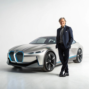 Dirk Nitsche presenting a futuristic BMW concept car design. The sleek vehicle is displayed on a plain background.