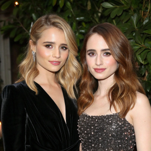 High-resolution close-up of Dianna Agron and Lily Collins. Dianna with blonde wavy hair and black velvet dress. Lily with auburn wavy hair and sparkling top. Lush green backdrop