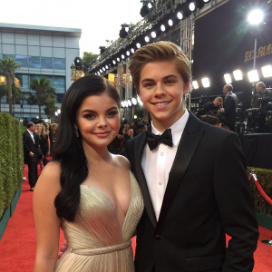 Ariel Winter and Laurent Claude Gaudette on the Emmy Awards red carpet. Posed in front of flashing cameras.