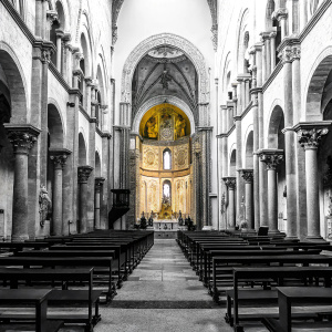 Inside the Basilica of Cefalù, Italy, stunning golden mosaics cover the walls. The grand central archway and numerous statues create a sacred atmosphere.