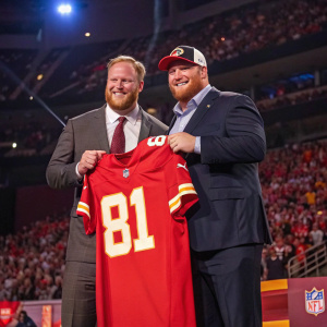Brandon Scherff and Roger Goodell on stage, presenting a custom jersey. The background features a packed stadium crowd.