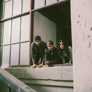 Matthew Daddario, Will Tudor, and Emeraude Toubia on set of Shadowhunters. Dimly lit, dramatic atmosphere, they pose in character.