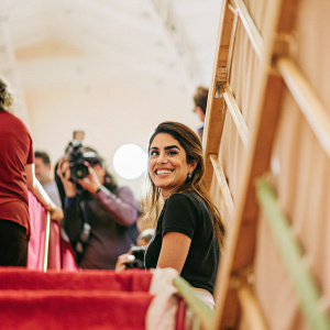 Nikki Reed, actress, wearing a casual black t-shirt. Smiling warmly. Crowded backstage area with photographers and crew.