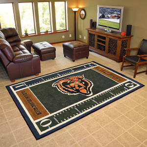 A living room featuring a Chicago Bears themed rug on a beige carpet. The rug is football-shaped with detailed lacing and the Bears emblem.