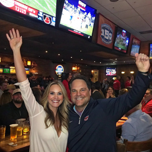 Alicia Rickter Piazza and Mike Piazza at a crowded sports bar, celebrating Baywatch's 30th Anniversary with fans.