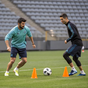 David Villa and Cristiano Ronaldo in intense training session at the football academy. Both wearing casual sportswear. Empty field backdrop.