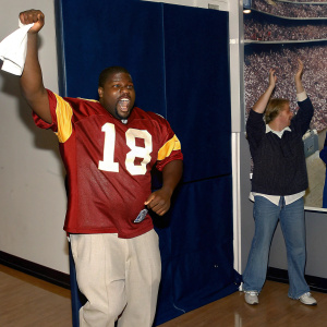 Darreus Rogers, in his USC Trojans jersey, celebrating wildly after a victorious football game. Stadium filled with cheering fans.