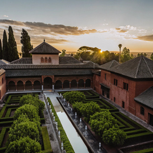 Aerial view of Alhambra palace complex at sunset. Richly detailed architecture. Lush gardens.