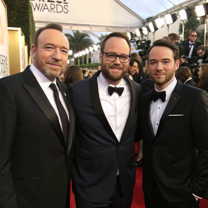 Kevin Spacey, Dana Brunetti, and Jason Musante Klein at the Golden Globe Awards. Wearing formal attire, posing together in front of red carpet with flashing cameras.