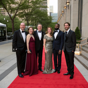 Cast members of 'The District' in formal attire. Craig T. Nelson, Lynne Thigpen, Jonathan Lapaglia, Elizabeth Marvel, Sean Patrick Thomas, and Roger Aaron Brown. They are standing outside a city hall. Backdrop shows trees and a red carpet.