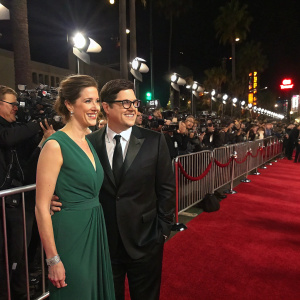 Rich Sommer and Virginia Donohoe attend a star-studded gala event. Rich in a tailored black suit, Virginia in an elegant emerald dress. Red carpet scene with flashing cameras and celebrity fans.