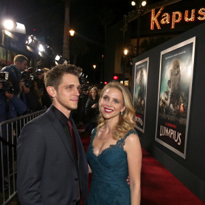 Zach Shields and Kelli Garner at the 'Krampus' premiere. Movie posters and flashing cameras in background.