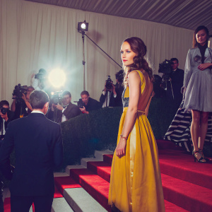 Keira Knightley, in a vibrant yellow dress, at the annual Met Gala. She stands confidently on the bustling red carpet.