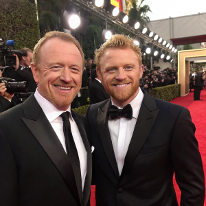 John Laseter and Kevin McKidd, smiling and in formal attire, at the Golden Globe Awards. Red carpet event, flashing cameras