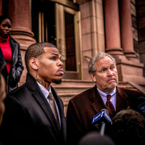 Chris Brown and his attorney Mark Geragos standing outside a courthouse. They are dressed in formal attire and are speaking to reporters.