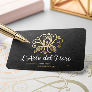 Business Card for L'arte del fiore. Logo: Gold stylized floral design on black background. Contact Info: Elegant script email and website. Background: Subtle blurred soft color design, professional and refined style.