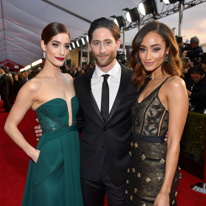 Janet Montgomery, Iddo Goldberg, and Ashley Madekwe at a glamorous awards show. Flashing lights and crowd visible in the background.