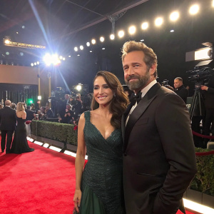 Zuria Vega and Gabriel Soto, dressed in formal wear, center stage at award show. Bright lights and camera flashes