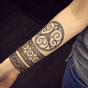 Detailed sketch of Korra's wrist tattoo. The intricate design is dark and swirls around her wrist. Dark background, close-up view.