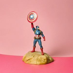 Realistic figurine of Captain America. Dynamic pose, detailed costume. Sculpted base with textured background. Comic book style.