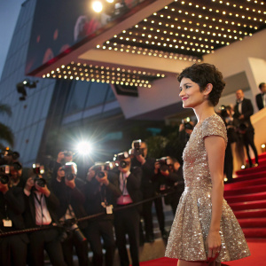 Audrey Tautou at Cannes Film Festival. Wearing a sparkling sequined dress. Poses elegantly on the red carpet surrounded by paparazzi.