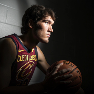 Cedi Osman, basketball player, posing with Cleveland Cavaliers logo. Dark and moody studio setting with dramatic lighting